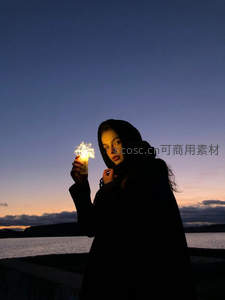 湖畔暮色里，女孩手持烟花棒凝望