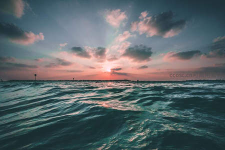 夕阳穿透云层洒向波涛大海