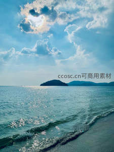 阳光穿透云层间，海面波光耀沙滩