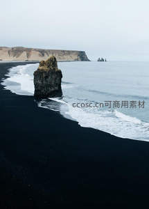 黑沙滩上的孤岩与远山海景