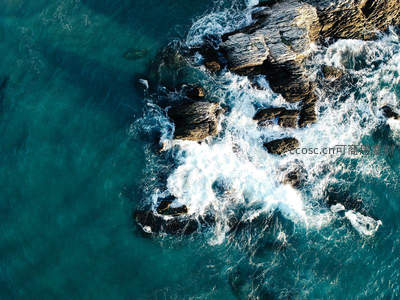 碧蓝海水拍打嶙峋礁石，激起朵朵浪花