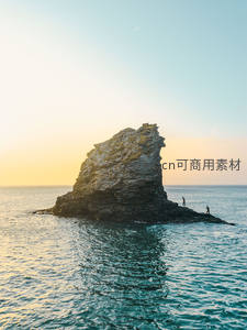 夕阳下的海上巨岩与探险者身影