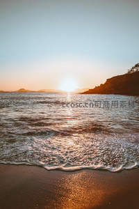 金色余晖，海浪轻吻沙滩岸