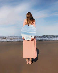 女子持镜映照天空的超现实海滩