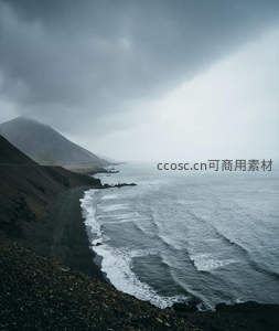 阴云密布黑沙滩，海浪拍岸显苍凉