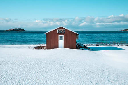 雪地中的红色小屋临海而立