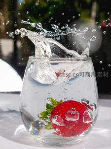 草莓沉入透明水杯，气泡环绕水花飞舞