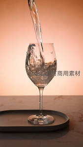 暖光下水流注入高脚酒杯