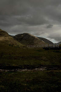 阴云笼罩下的荒凉山谷与溪流