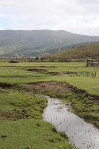 溪流蜿蜒穿过绿野牧场与远山