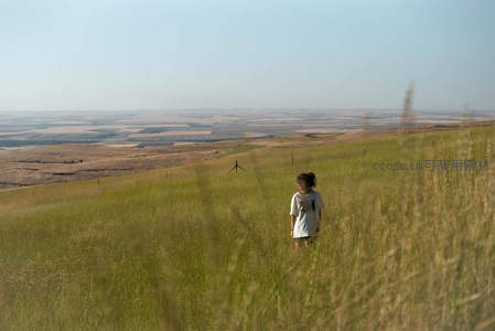 孩童漫步金色草坡，远眺大地如画