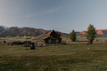 草原木屋静立山脚，远眺彩丘与雪峰