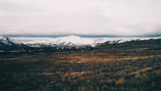 雪峰下的荒原与远处城镇剪影