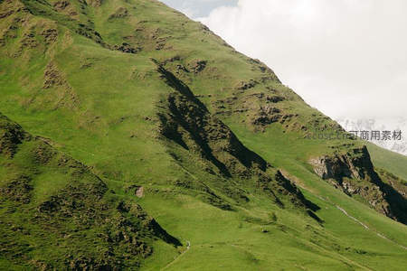 陡峭绿坡映衬雪峰云海