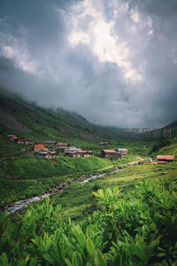 云雾缭绕山谷村，溪流穿行绿意间