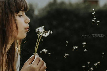 侧脸少女吹散蒲公英种子