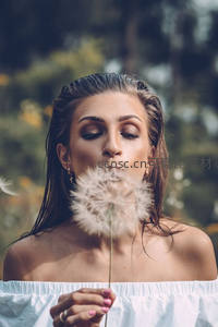 女子轻吹蒲公英许愿时刻