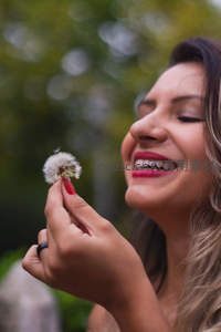 女子微笑吹散蒲公英，享受惬意时光