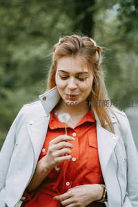 女子微笑轻吹手中蒲公英许愿