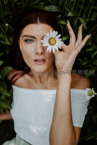 女子手持雏菊遮眼的优雅人像