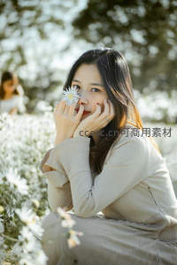 花丛中少女手持雏菊微笑