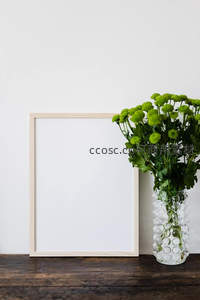 绿菊与空白画框并置的极简家居摆设