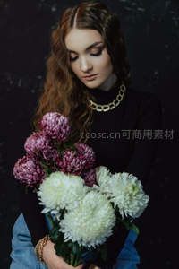 女子怀抱白紫菊花凝视花丛