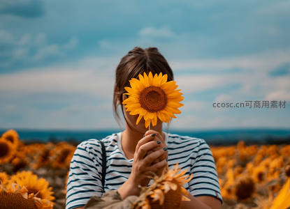 女子手捧向日葵遮面，花海背景意境悠然