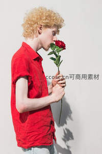 金发青年轻嗅红玫瑰，侧影温柔