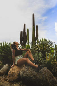 女子岩石上仰望仙人掌