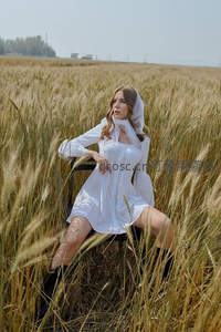 白衣女子坐于麦浪间，享受田野的静谧时光