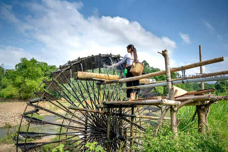 女子在竹制水车旁劳作