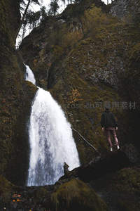旅人伫立崖边，凝望深谷中奔腾的白色瀑布