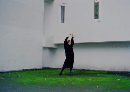 白衣墙前舞者舒展，绿茵映衬优雅姿态