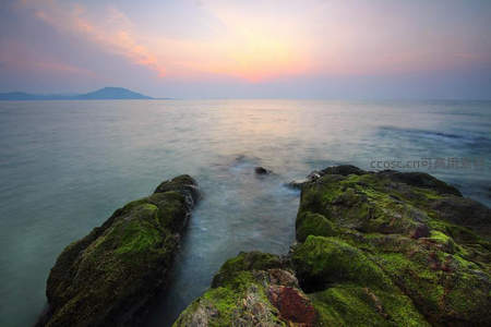 暮色海岩，青苔覆石映霞光