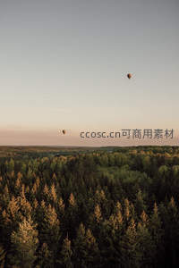 热气球飘浮林海上空黄昏时分
