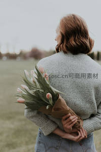 女子怀抱郁金香伫立田野间