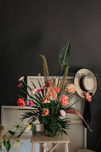 深色背景下的热带花卉与草帽装饰