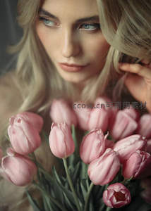 金发女子手抚粉色郁金香凝视镜头