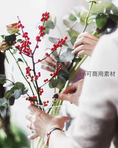 双手精心插花，红果绿叶相映成趣