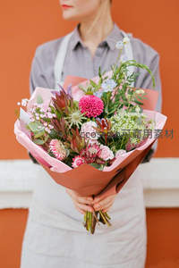 花艺师怀抱春日花束，橙墙映衬温馨时光