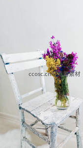 干花插于玻璃瓶，置于斑驳白椅之上