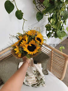 手提向日葵花束，绿植环绕温馨