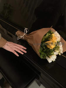 牛皮纸包裹的黄白花束与钢琴旁的手