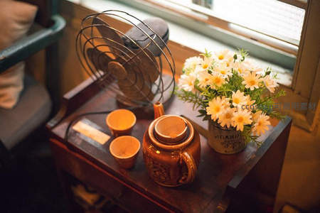 复古风扇旁的茶具与雏菊，温馨午后时光
