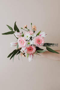 手握粉白花卉组合花束近景