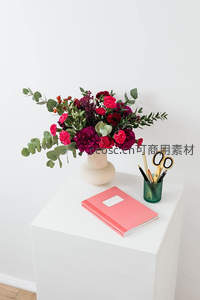 办公桌上的温馨花束，粉色笔记本与文具相伴