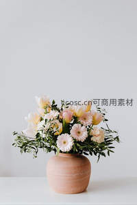 粉色系鲜花插于陶罐静置桌面