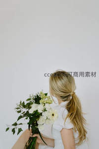 金发女子背影手持白花束，简约纯净