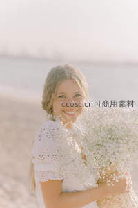 海边微笑女子怀抱满天星花束沐浴阳光